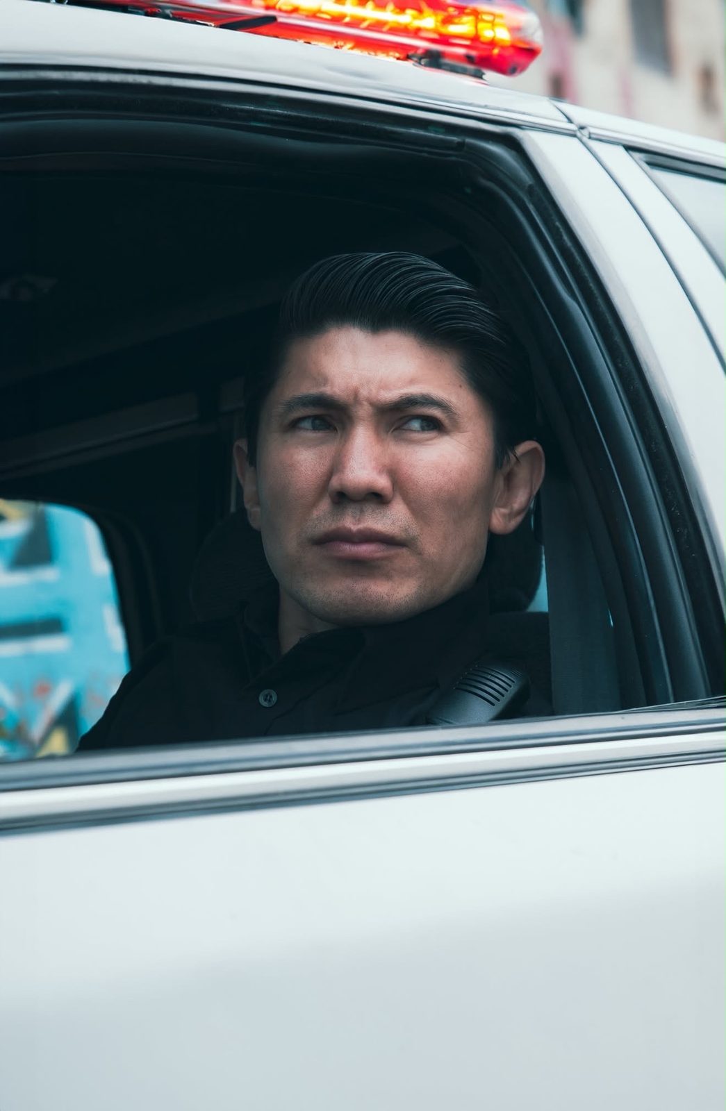 Medet Aman in a patrol car window under a glowing light bar